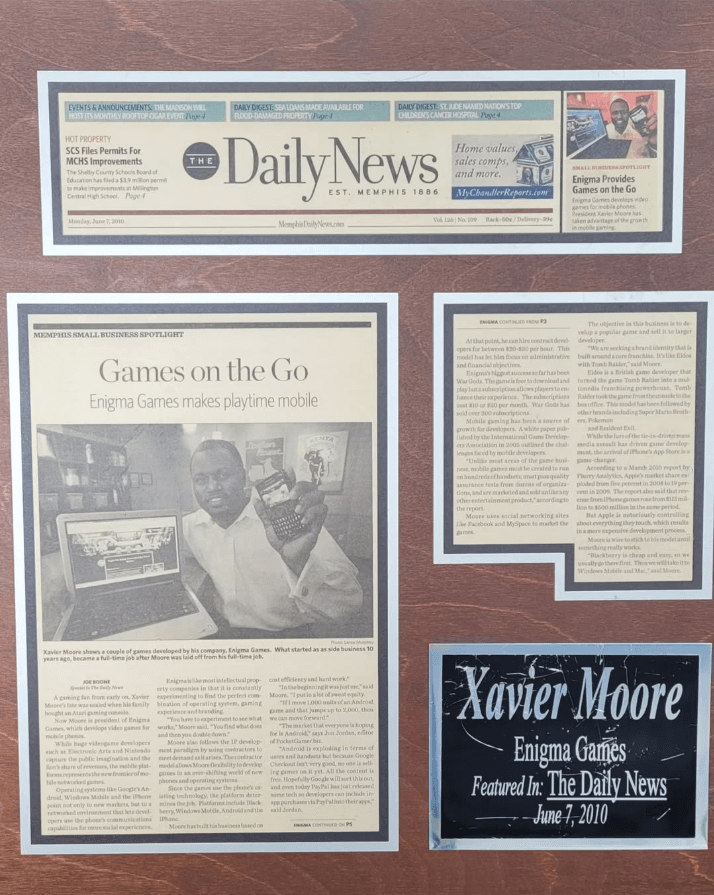 Framed newspaper clipping from The Daily News Memphis small business spotlight featuring Enigma Games under the headline Games on the Go